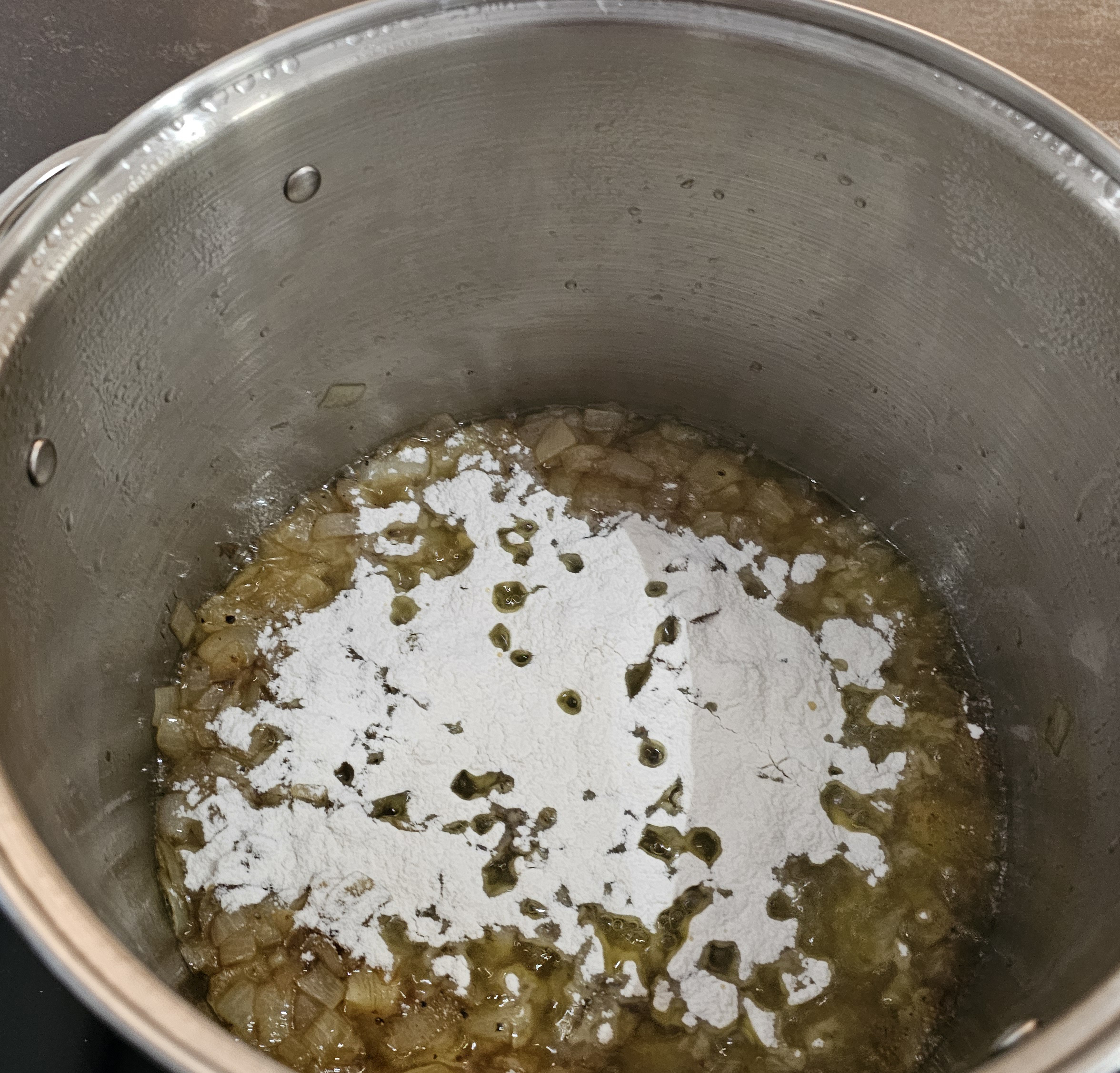 Pot with onions, oil, and flour sprinkled on top